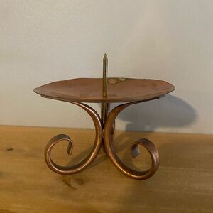 A vintage Gregorian copper candle holder with a scrolled handle.